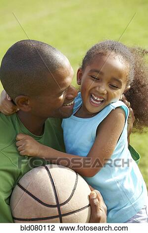 Stock Image - African American father hugging daughter. Fotosearch