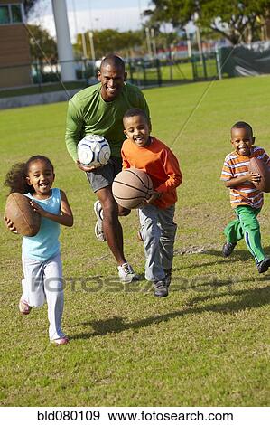 Stock Photo - African American father playing ball with children. Fotosearch