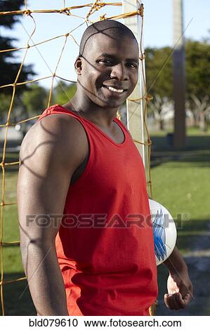 Stock Image - Black man holding soccer ball. Fotosearch