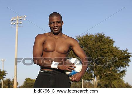 Stock Image - Black man holding soccer ball. Fotosearch