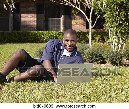 Stock Image - Black man typing on laptop. Fotosearch