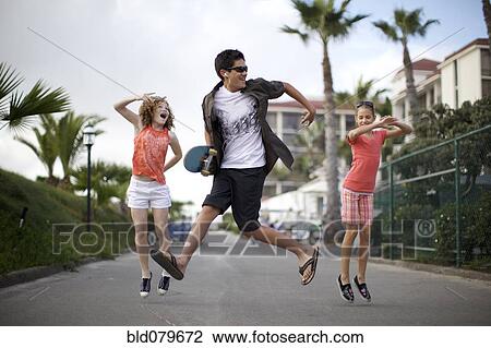 Stock Image - Friends jumping on urban sidewalk. Fotosearch
