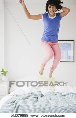 Hispanic woman jumping on bed View Large Photo Image Stock Photo - Hispanic woman jumping on bed. Fotosearch