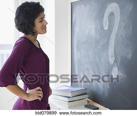 Stock Photo - Hispanic woman looking at question mark on blackboard. Fotosearch