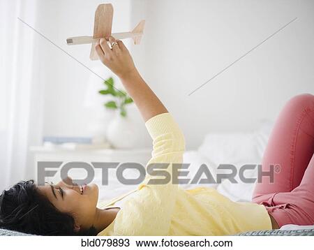 Hispanic woman playing with toy airplane View Large Photo Image Stock Image - Hispanic woman playing with toy airplane. Fotosearch