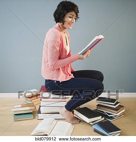 Stock Image - Hispanic woman reading books. Fotosearch