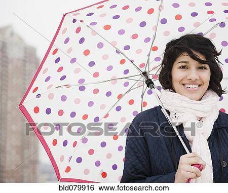 Stock Photograph - Hispanic woman walking in city with umbrella. Fotosearch