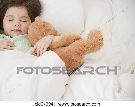 Stock Image - Mixed race girl sleeping with teddy bear. Fotosearch