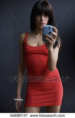 Stock Image - Mixed race woman text messaging on cell phone. Fotosearch