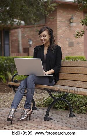 Stock Photo - Mixed race woman typing on laptop. Fotosearch
