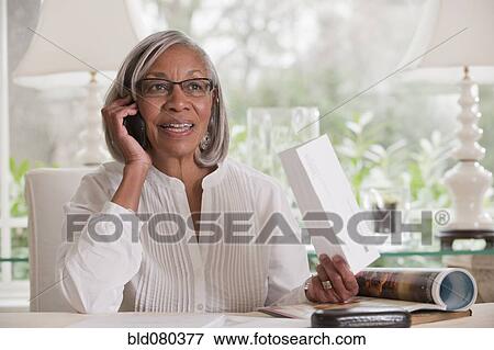 Black woman holding paper talking on cell phone View Large Photo Image Stock Photo - Black woman holding paper talking on cell phone. Fotosearch