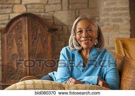 Black woman sitting on sofa View Large Photo Image Stock Image - Black woman sitting on sofa. Fotosearch