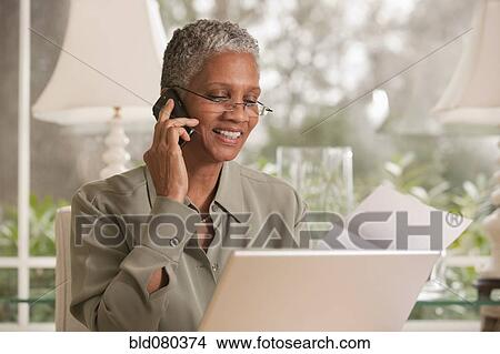 Black woman talking on cell phone and using laptop View Large Photo Image Picture - Black woman talking on cell phone and using laptop. Fotosearch