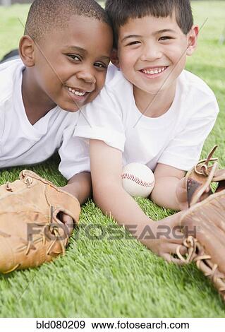 Stock Photo - Boys laying in grass with baseball and baseball gloves. Fotosearch