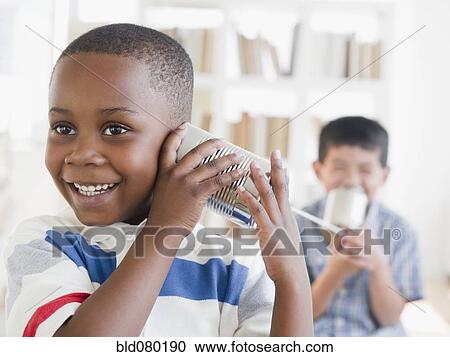 Stock Image - Boys playing with tin can telephone. Fotosearch