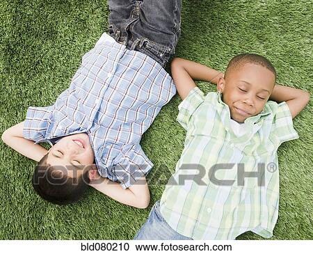 Stock Image - Boys sleeping in grass. Fotosearch