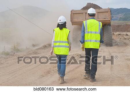 Construction workers walking behind dump truck View Large Photo Image Stock Image - Construction workers walking behind dump truck. Fotosearch