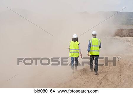 Picture - Construction workers walking in cloud of dust. Fotosearch