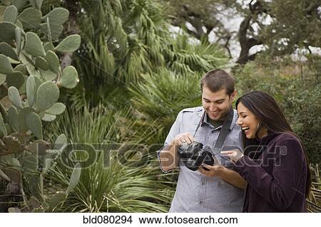 Picture - Couple looking at pictures on digital camera. Fotosearch