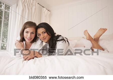 Stock Photography - Friends laying on bed together. Fotosearch