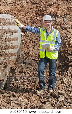 Stock Photo - Hispanic construction worker standing in dirt. Fotosearch