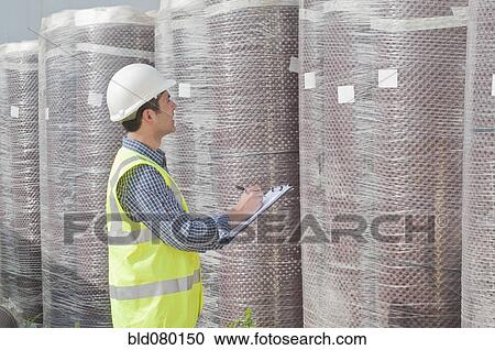 Stock Image - Hispanic construction worker writing on clipboard. Fotosearch