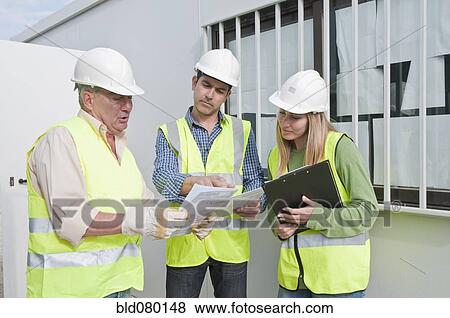 Hispanic construction workers reviewing paperwork View Large Photo Image Stock Photo - Hispanic construction workers reviewing paperwork. Fotosearch