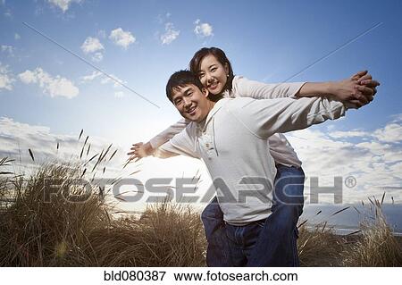 Stock Photo - Korean man giving girlfriend piggyback ride. Fotosearch