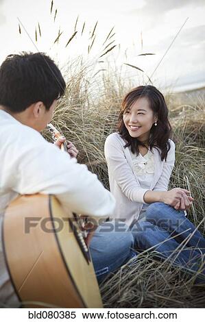Stock Photography - Korean man playing guitar for girlfriend. Fotosearch