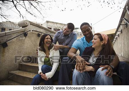 Stock Image - Laughing couples sitting on steps together. Fotosearch