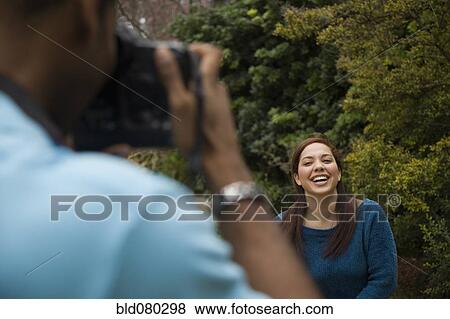 Stock Photo - Man taking picture of smiling girlfriend. Fotosearch
