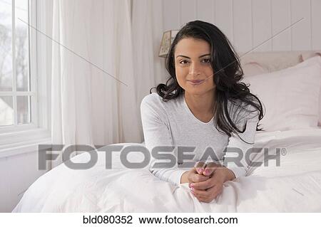 Stock Image - Middle Eastern woman laying on bed. Fotosearch