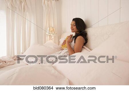 Picture - Middle Eastern woman reading in bed. Fotosearch