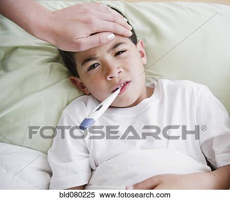 Stock Photography - Sick mixed race boy having is temperature taken. Fotosearch