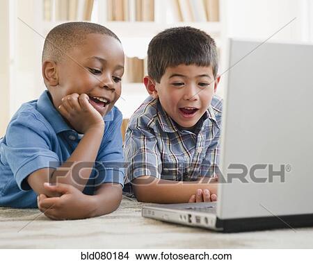 Picture - Smiling boys enjoying using a laptop. Fotosearch