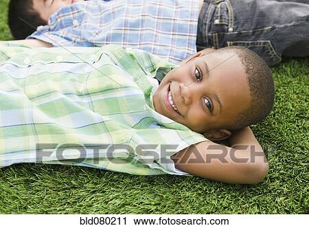 Stock Image - Smiling boys laying in grass. Fotosearch