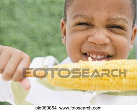 Picture - African American boy eating corn on the cob. Fotosearch