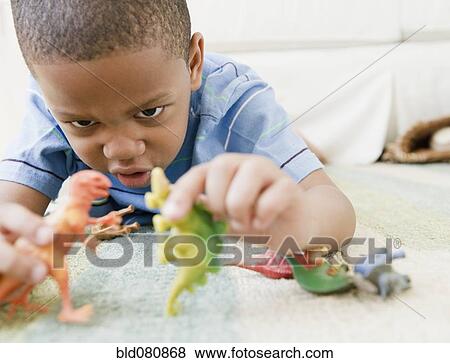 African American boy laying on floor playing with toy dinosaurs View Large Photo Image Stock Photo - African American boy laying on floor playing with toy dinosaurs. Fotosearch
