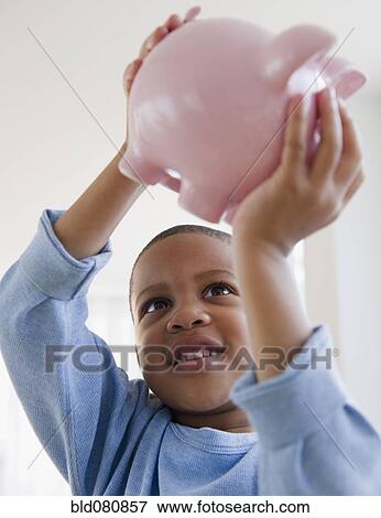 African American boy lifting piggy bank View Large Photo Image Stock Photo - African American boy lifting piggy bank. Fotosearch