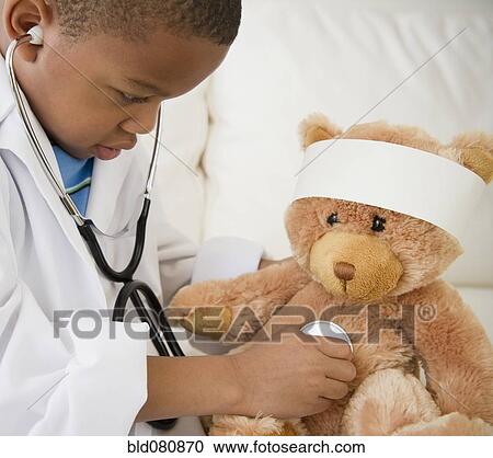 Stock Image - African American boy playing doctor with teddy bear. Fotosearch