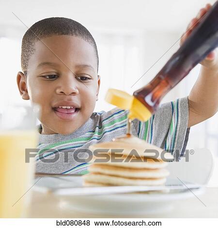 African American boy pouring syrup on pancakes View Large Photo Image Stock Photo - African American boy pouring syrup on pancakes. Fotosearch