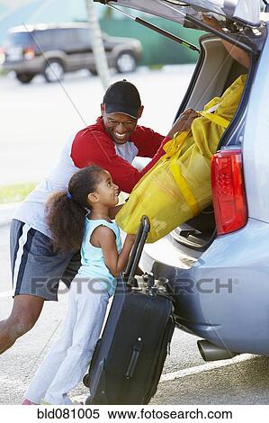 Stock Photography - African American father and daughter loading car. Fotosearch