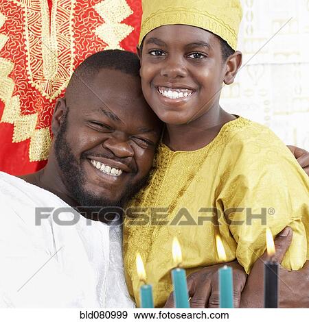 Stock Photo - African American father hugging son in traditional clothing. Fotosearch