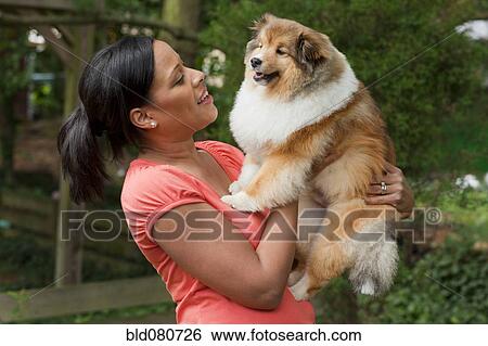 Stock Photograph - African American woman holding dog. Fotosearch
