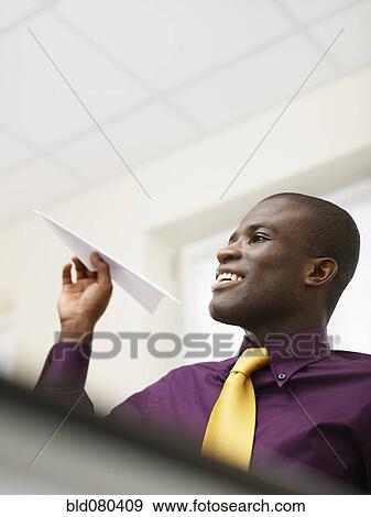 Stock Photo - Black businessman throwing paper airplane. Fotosearch