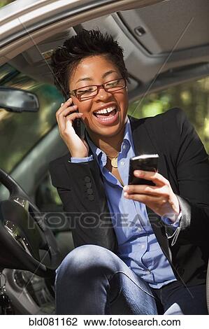 Black woman in vehicle using two cell phones View Large Photo Image Stock Image - Black woman in vehicle using two cell phones. Fotosearch
