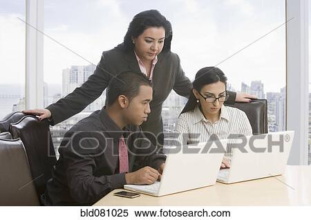 Stock Photography - Business people in meeting using laptops. Fotosearch
