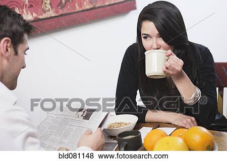 Stock Photo - Couple eating breakfast and reading newspaper. Fotosearch