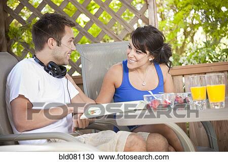 Stock Image - Couple eating breakfast on patio. Fotosearch