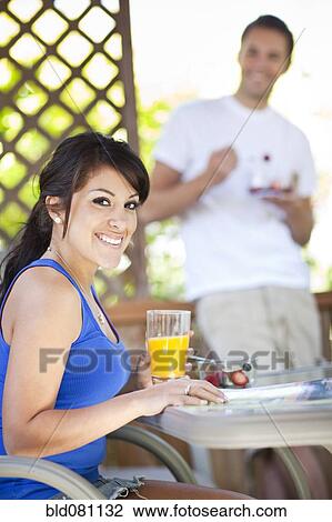 Stock Image - Couple eating breakfast on patio. Fotosearch